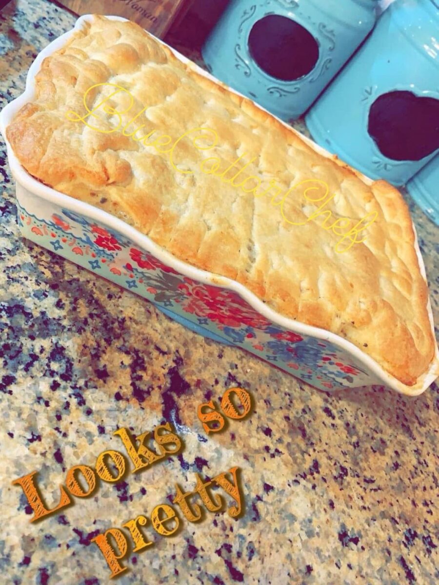A golden-brown baked pie sits in a colorful floral dish on a granite countertop. Blue canisters are in the background. The words Looks so pretty are overlaid on the image.
