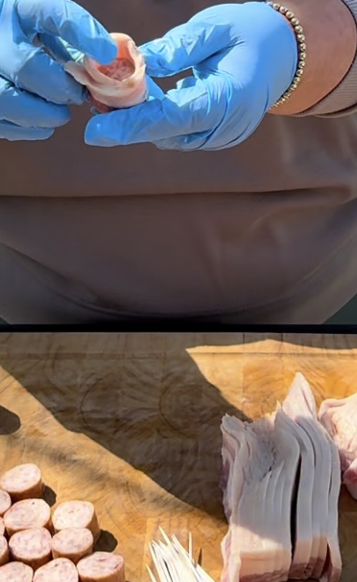 A person wearing blue gloves holds a piece of sliced sausage wrapped in bacon. Below, a wooden cutting board displays several sausage slices, bacon strips, and wooden toothpicks.