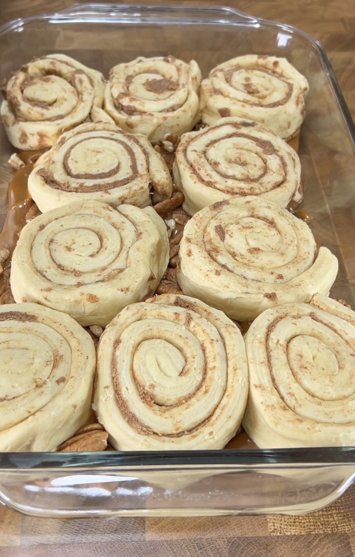 Unbaked cinnamon rolls arranged in a glass baking dish, showing swirls of dough and cinnamon sugar filling, ready to be baked.