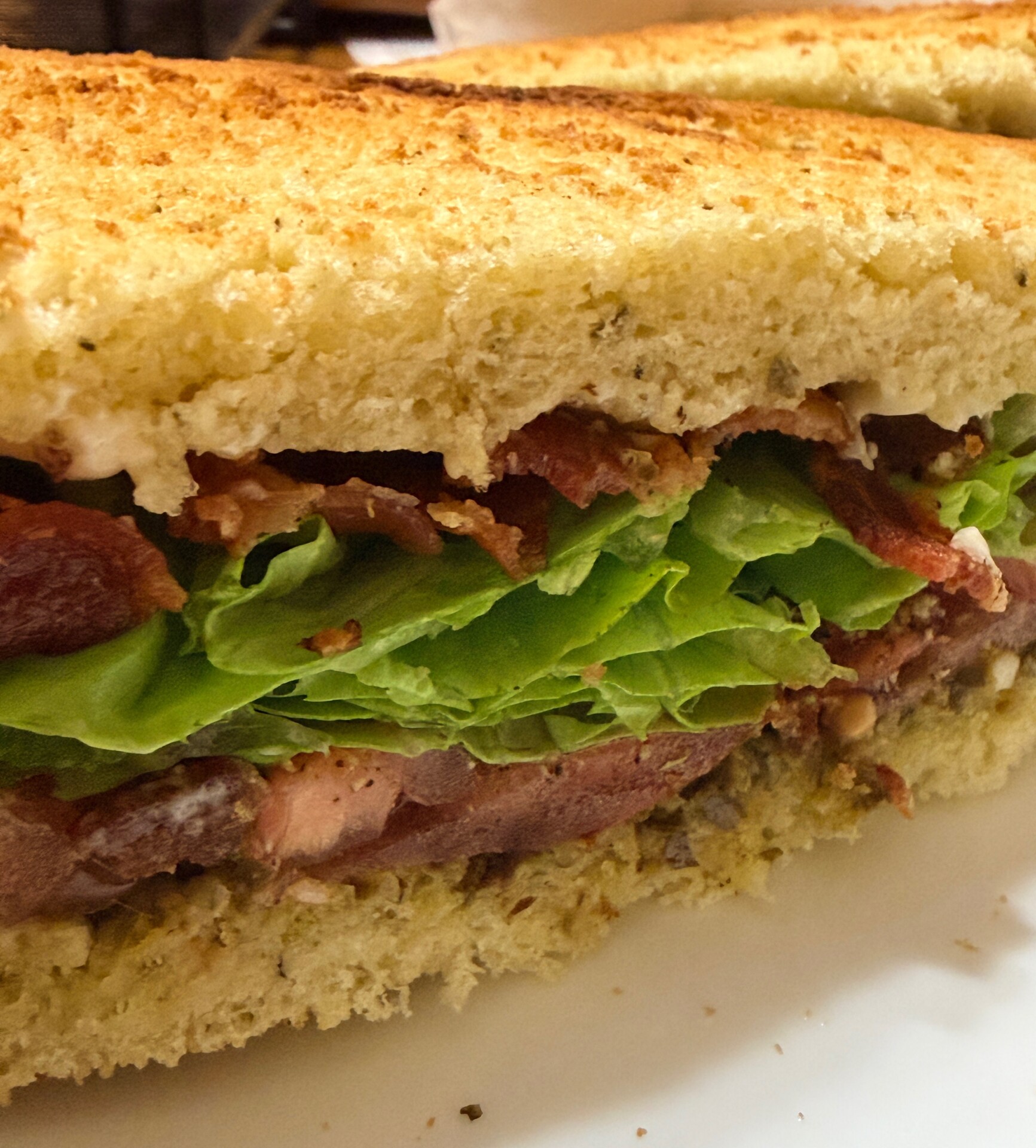 A close-up of a BLT sandwich showing layers of crispy bacon, fresh lettuce, tomatoes, and toasted bread.