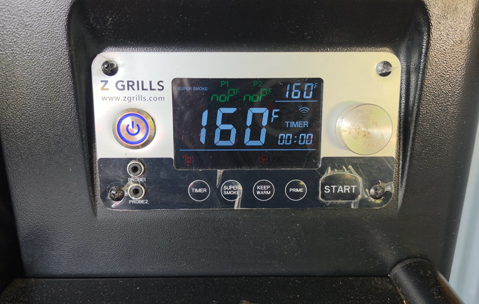 Close-up of a Z Grills digital control panel showing a temperature of 160°F, with various buttons including power, start, and settings for super smoke, keep warm, and timer.