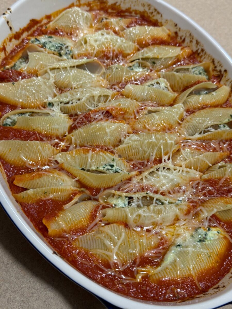 A baking dish filled with jumbo pasta shells stuffed with ricotta and spinach, topped with tomato sauce and melted cheese.
