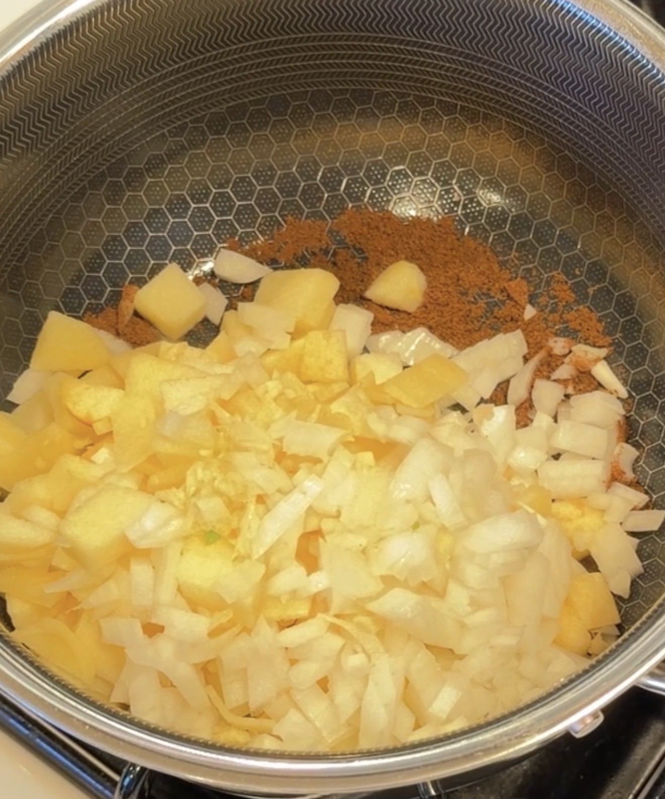 Diced potatoes and onions cooking in a pan with brown spices.