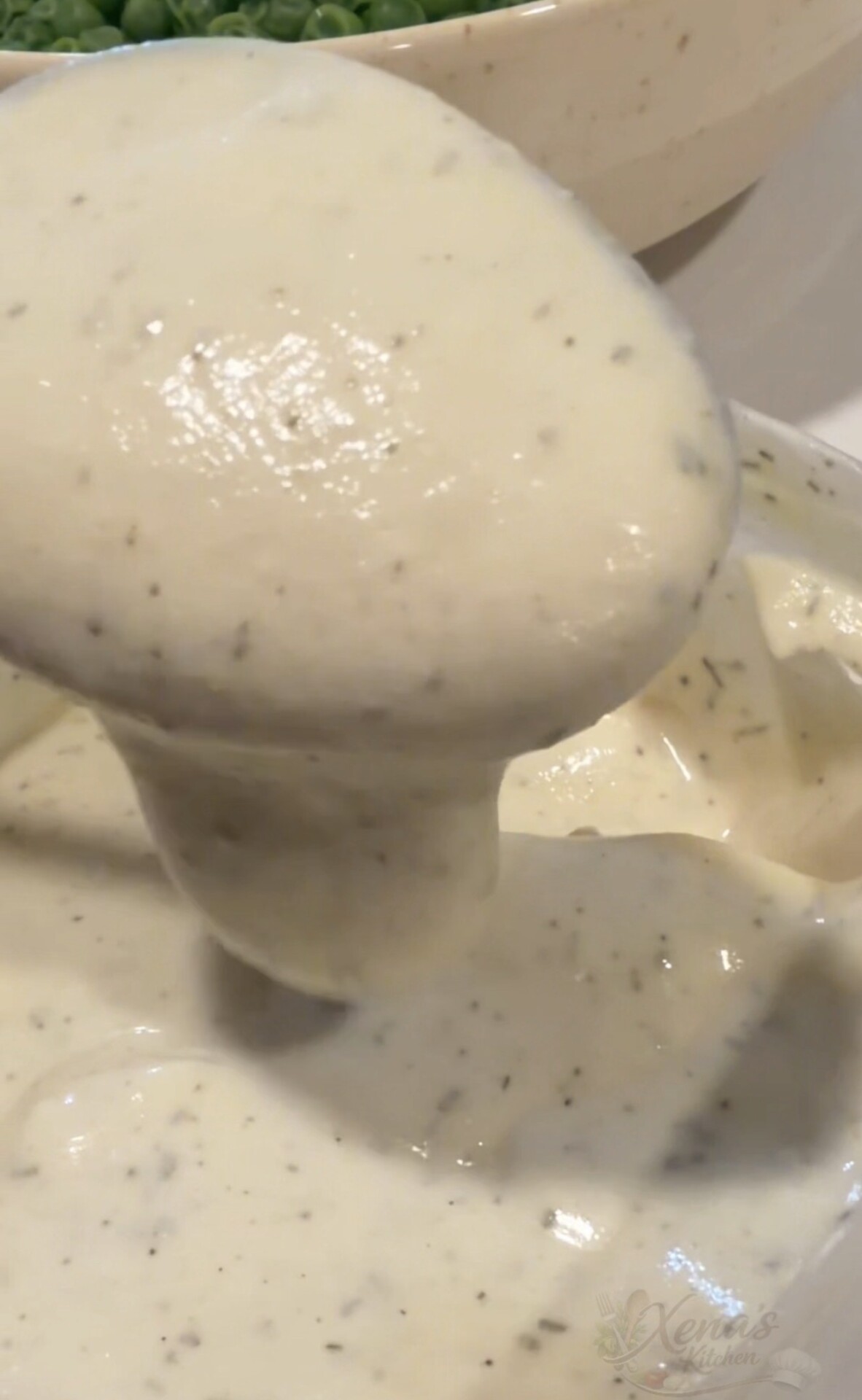 A large spoonful of creamy, herb-flecked sauce being lifted from a bowl.