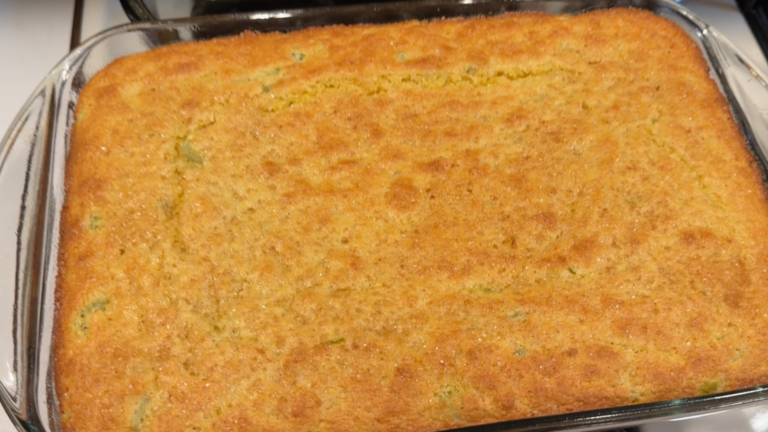 A freshly baked rectangular pan of cornbread with visible green bits inside.