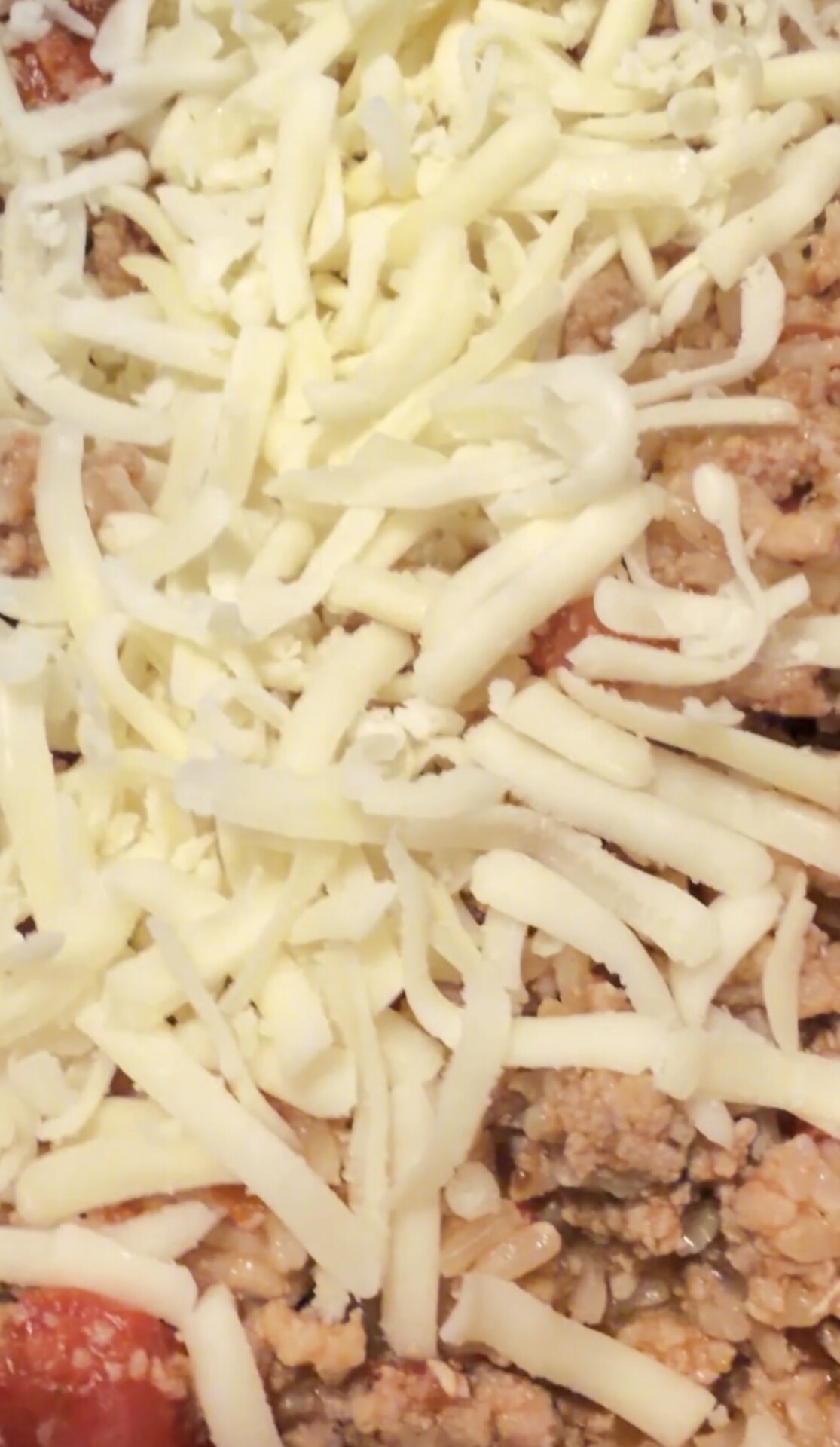 Ground meat, rice, and tomato sauce topped with shredded cheese.