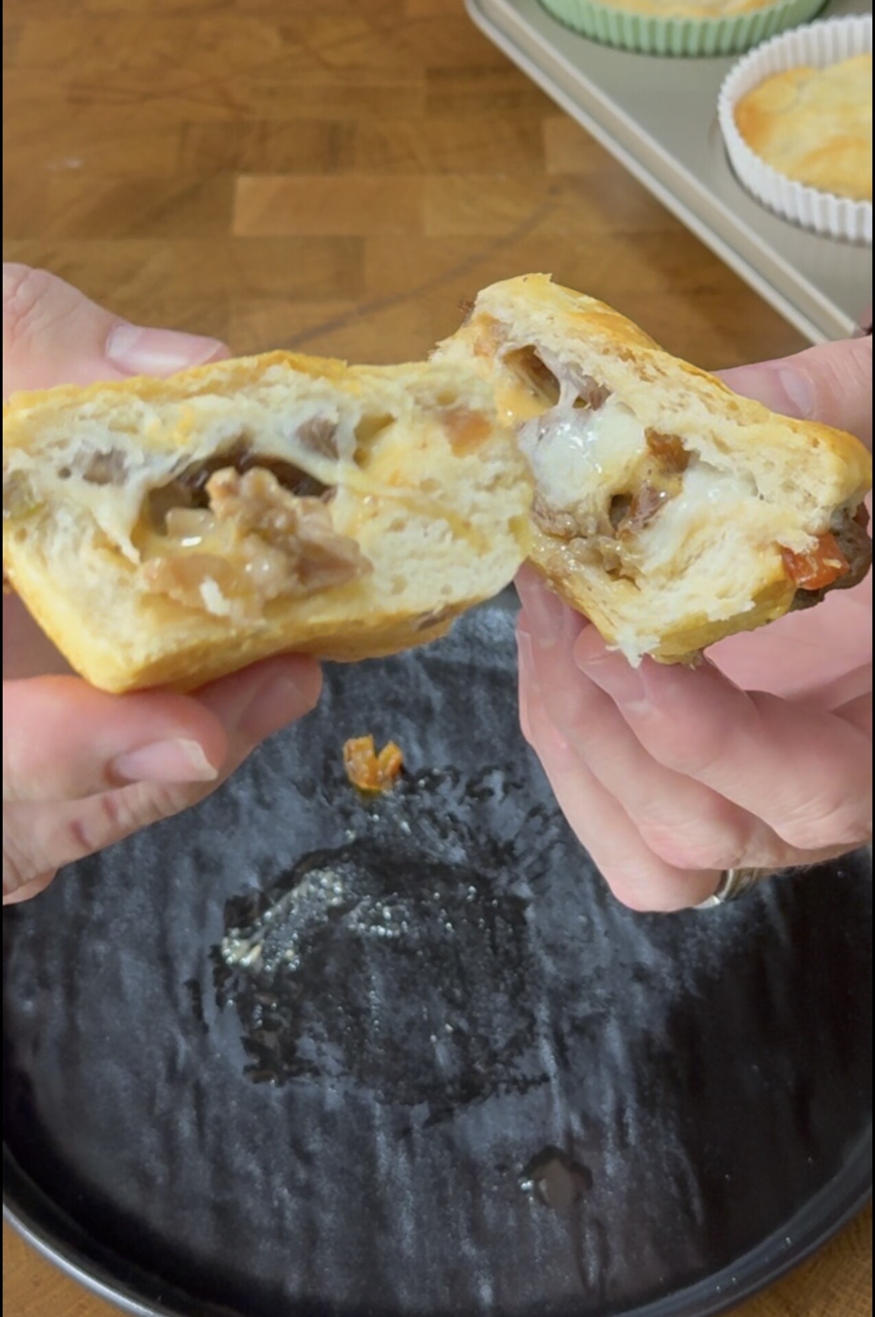 Hands pulling apart a savory pastry filled with melted cheese and meat.
