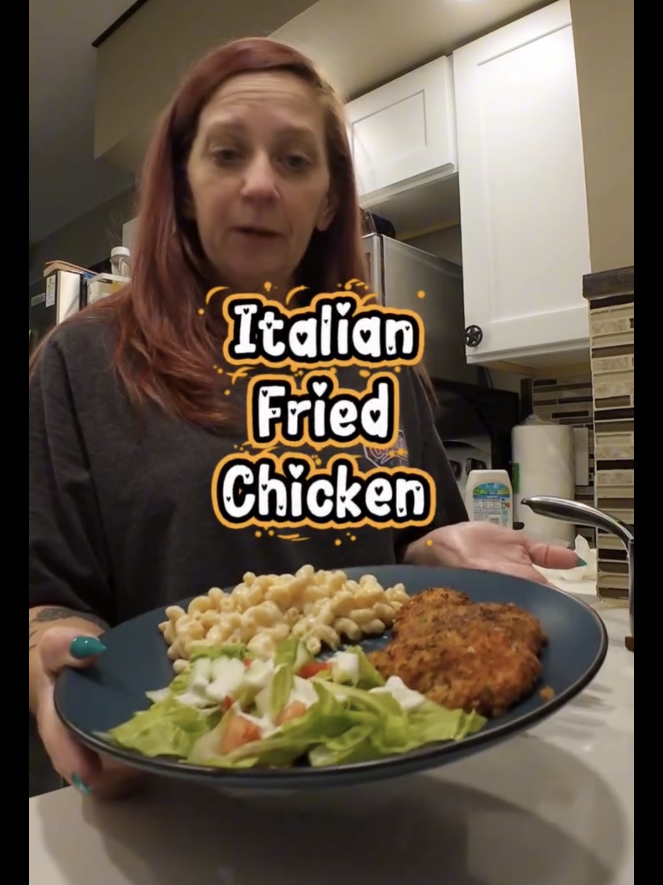 A woman holds a plate with Italian fried chicken, macaroni, and a side salad.