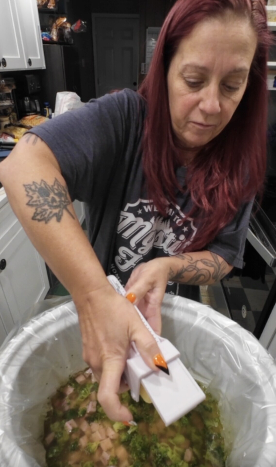 A woman using a handheld cheese grater over a slow cooker filled with soup.
