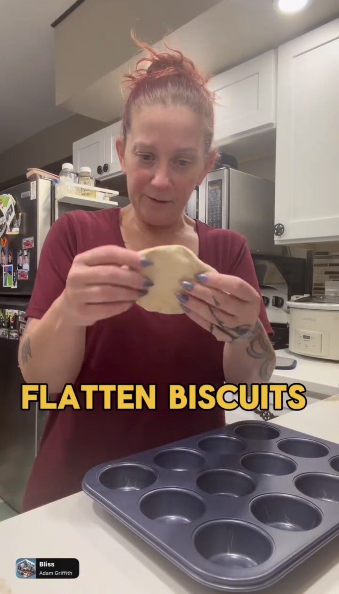 A person flattening a piece of dough in a kitchen with a muffin tin in the foreground.