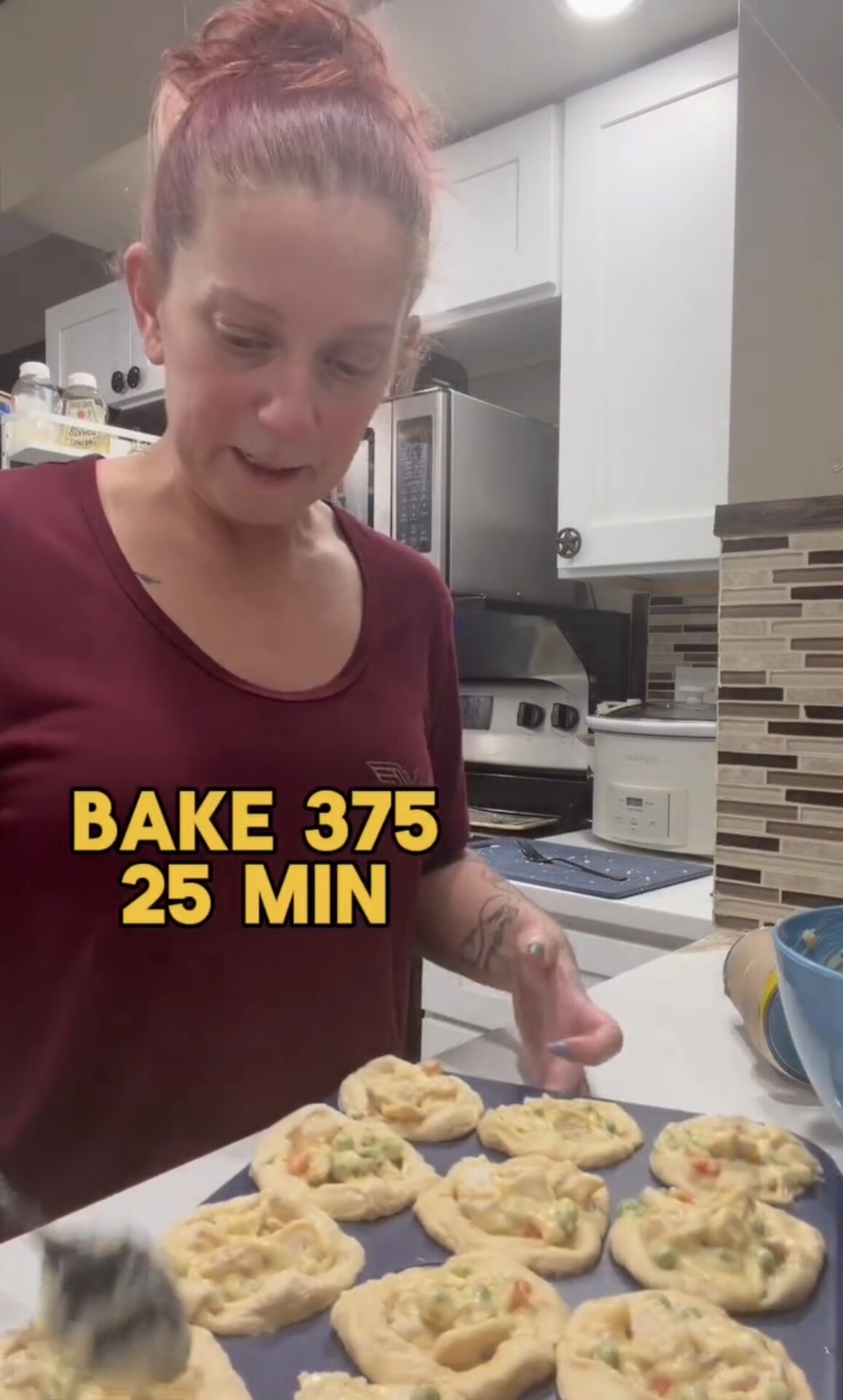 A person in a maroon shirt prepares a baking sheet of dough circles filled with a vegetable mixture, with the text overlay BAKE 375 25 MIN visible.