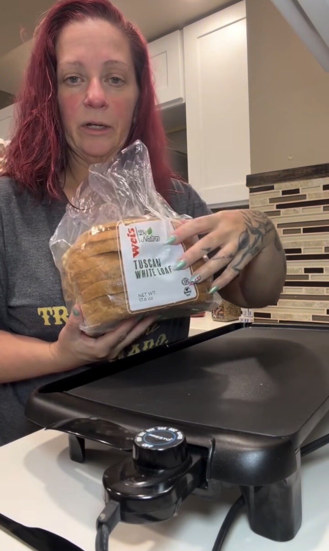 A woman holds a loaf of Weis By Nature Tuscan white bread in front of an electric griddle.