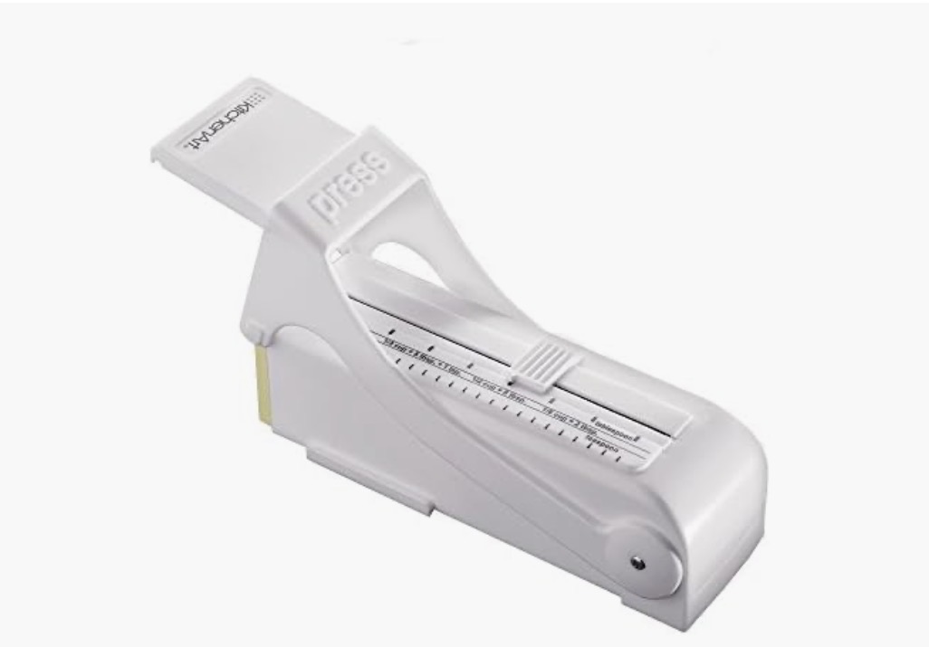 White KitchenArt adjustable measuring tool with a sliding selector and printed volume markings.