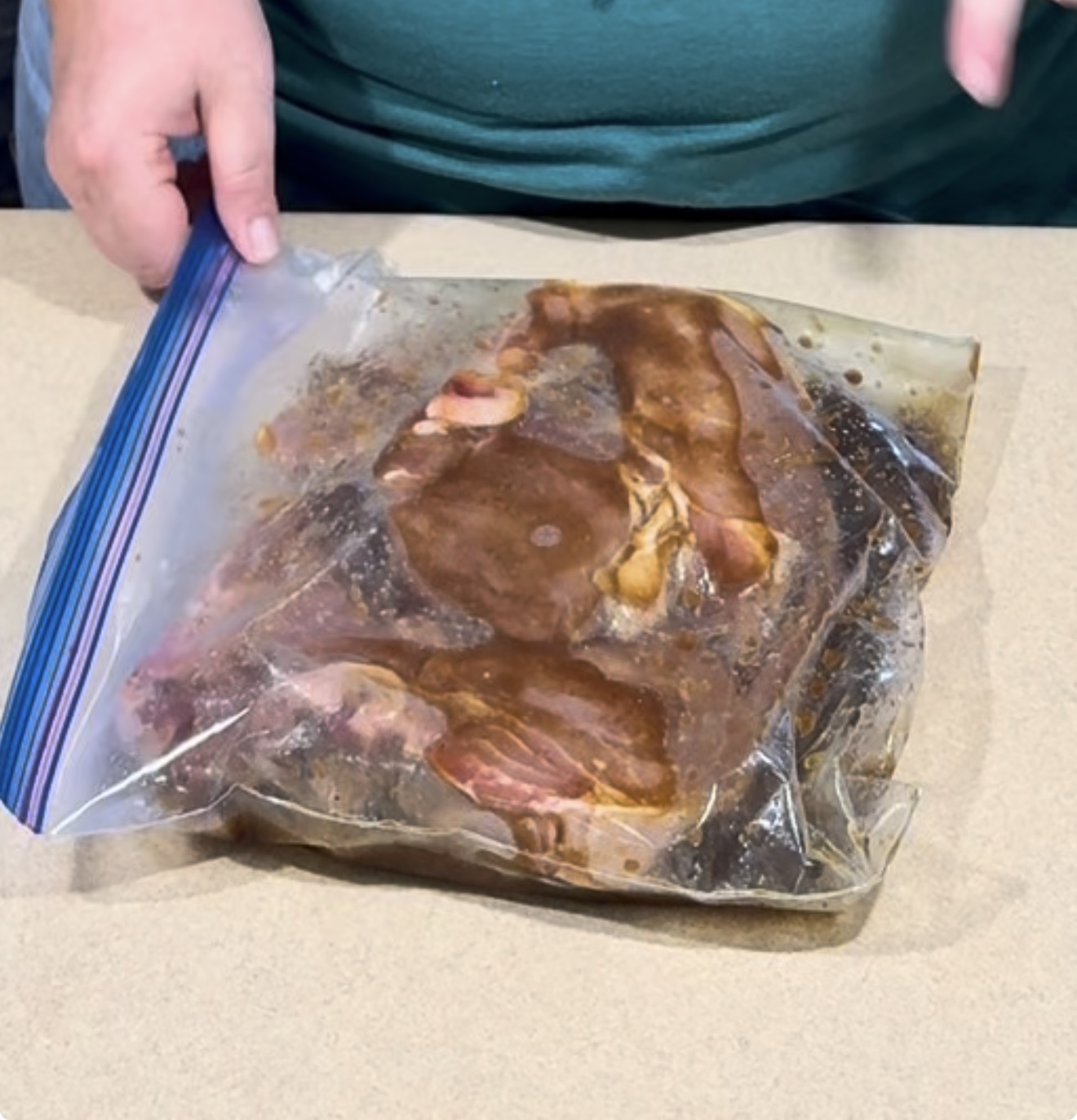 Raw meat marinating in a sealed plastic zip-top bag.