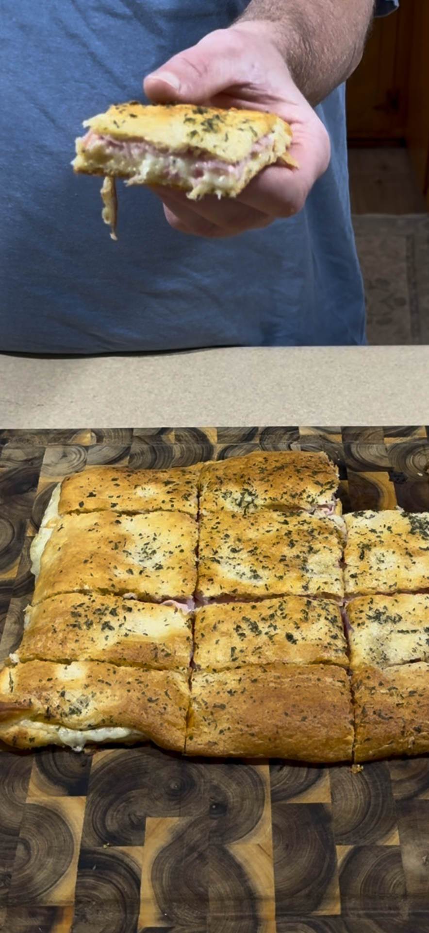 A hand holds a square slice of ham and cheese stuffed bread above a cutting board filled with similar sliced squares.